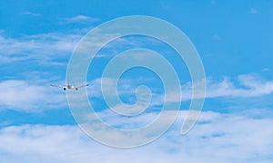 Commercial airline flying on blue sky and white fluffy clouds. Airplane flying on sunny day. Rear view of international flight