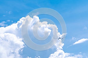 Commercial airline flying on blue sky and white fluffy clouds. Airplane flying on sunny day. Rear view of international flight