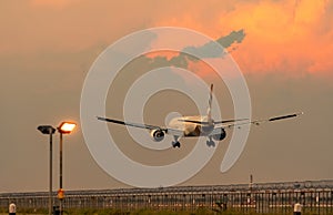 Commercial airline. Passenger plane landing at airport with beautiful sunset sky and clouds. Arrival flight. Airplane flying