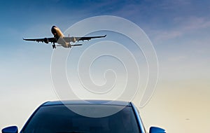 Commercial airline. Passenger plane landing approach blue SUV car at airport with blue sky and clouds at sunset. Arrival flight.