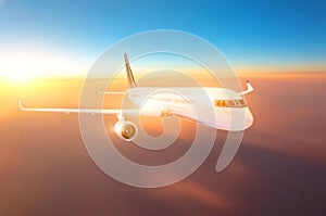 Commercial airplane flying above clouds in bright grdient sunset light