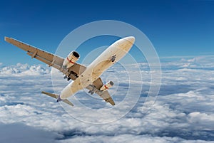 Commercial airplane flying above clouds and clear blue sky over