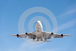 Commercial airplane flying in blue sky, full flap and landing ge