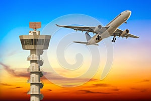 Commercial airplane take off over airport control tower at sunse