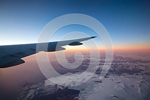 Commercial Aviation Jetplane flying over the ice mountain landscape on the Ocean Coast of Greenland.