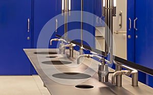 Commercial bathroom for hand washing. Faucets with a washbasin in a public toilet are blue.