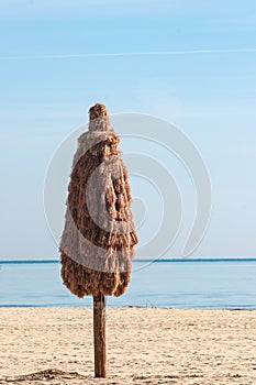 Commercial beach umbrella, closed, on a sandy beach, in early morning light