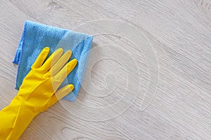 Commercial cleaning company concept. Hand in rubber protective glove with blue microfiber cloth is wiping floor. Copy space