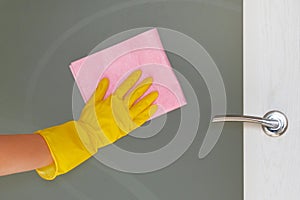 Commercial cleaning company concept. Hand in rubber protective glove with pink microfiber cloth is wiping glass door