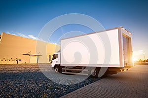 Commercial delivery truck with blank white trailer on cargo parking.