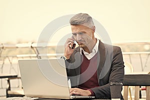 Commercial employee make phone call working on laptop in internet cafe outdoors, conference