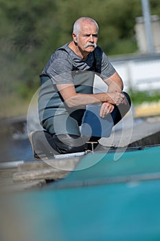 commercial fish farmer knelt at waters adge photo