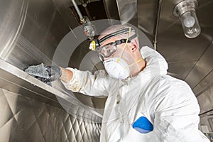 Commercial kitchen worker washing up at sink in professional kitchen