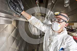 Commercial kitchen worker washing up at sink in professional kitchen