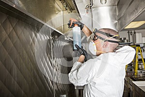 Commercial kitchen worker washing up at sink in professional kitchen