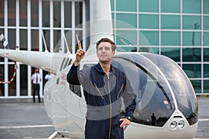 Commercial man pilot in technician suit standing in front of helicopter after check and maintenance engine