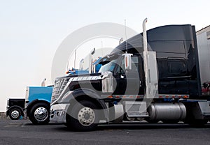 Commercial modern and classic semi trucks in truck stop line