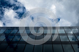 Commercial modern glass office building against cloudy sky in perspective