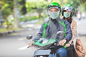 Commercial motorcycle taxi driver taking his passenger to her de photo