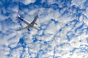 Commercial passenger airplane jet flying in dramatic clouds in sky altitude. Travel concept and tourism
