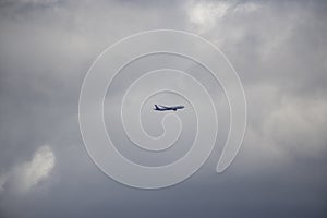 Commercial passenger jet aircraft departing Near sunset in a yellow and grey coloured cumulonimbus cloud.