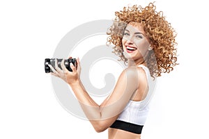 Commercial style portrait of a ginger, frizzy-haired woman holding a camera