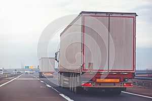 Commercial trailer truck in motion on freeway on cloudy afternoon