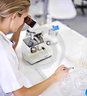 Committed to finding a cure. a beautiful young scientist recording her findings on a tablet.