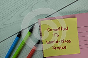 Committed To World-Class Service write on sticky notes isolated on Wooden Table