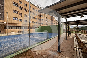 Common areas of an urbanization with a tennis court with gates and gazebos with wooden benches