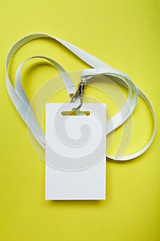 A common blank label name tag hanging on the neck with a red thread. Empty layout isolated on yellow