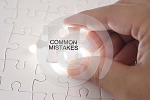 COMMON MISTAKES word on jigsaw puzzle. Businessman hands holding photo