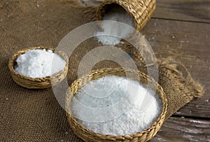 Common salt. Coarse grained salt on sack background and straw b