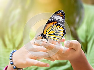 Common Tiger butterfly hanging on girl's finger