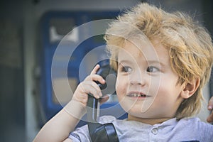 Communication, call on retro phone. Black handset in child little tender hand. Joyful boy speaks on the phone and looks