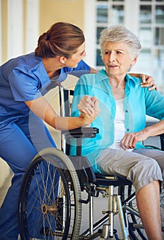Communication, caregiver or old woman in a wheelchair in hospital helping an elderly patient for support. Speaking