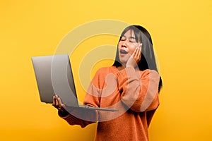 communication concept asian girl use laptop at home yellow studio photo She is happy to spend her free time online while