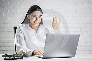 Communication concept with young pretty woman chating with collegue via online video service by laptop isolated on white brick