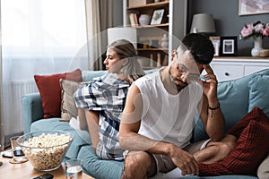 Communication problems, relationship difficulties. Young couple man and woman sitting on sofa at home, not talking after argue and