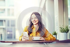 Happy woman texting on smartphone at city cafe photo