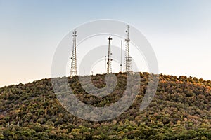 Communication tower antennas on the top of hill with forest.