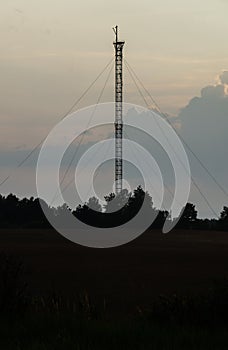 Communication tower on the background of twilight in the field