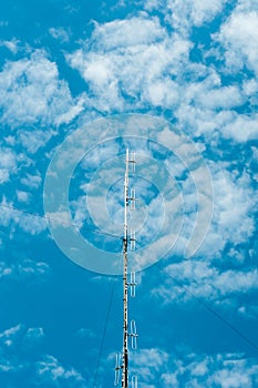 Communication tower with cell phone antenna on bright blue sky