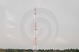 Communication tower of mobile and cellular devices with antennas on the background of a gray sky