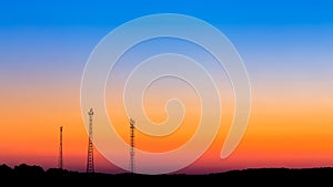 Communication towers far on sunrise sky background