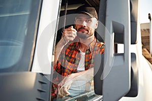 Communication by using radio. Young truck driver in casual clothes