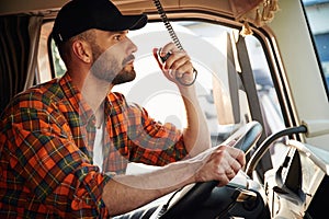 Communication by using radio. Young truck driver in casual clothes