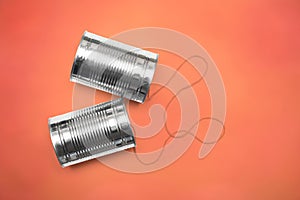 Communications and business calls concept of tin can telephone with string on orange