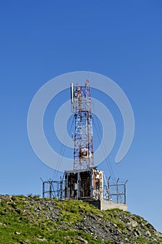 Communications cellular telecoms communications antenna in the top of the mountains with rusty communication shelter .