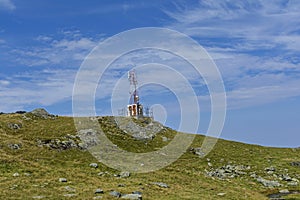 Communications cellular telecoms communications antenna in the top of the mountains with rusty communication shelter .